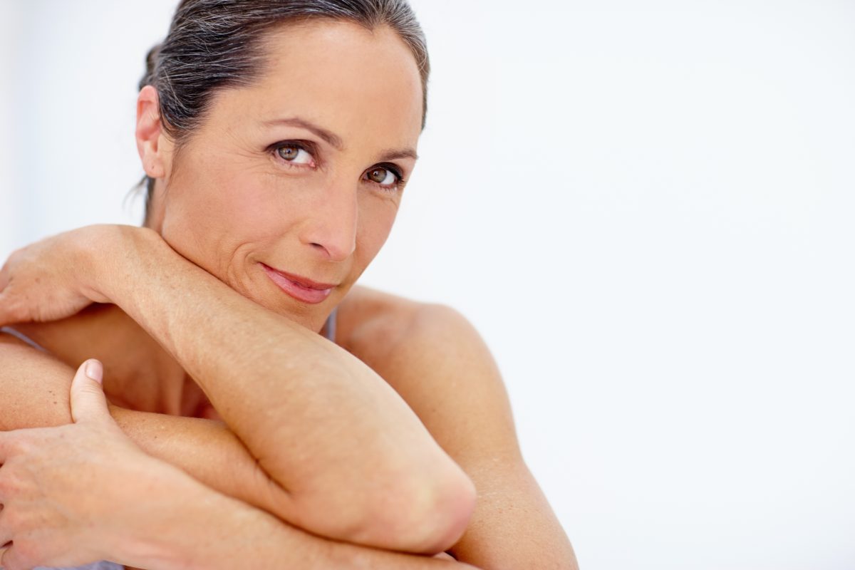 Woman with naturally healthy, glowing skin smiling in soft natural light